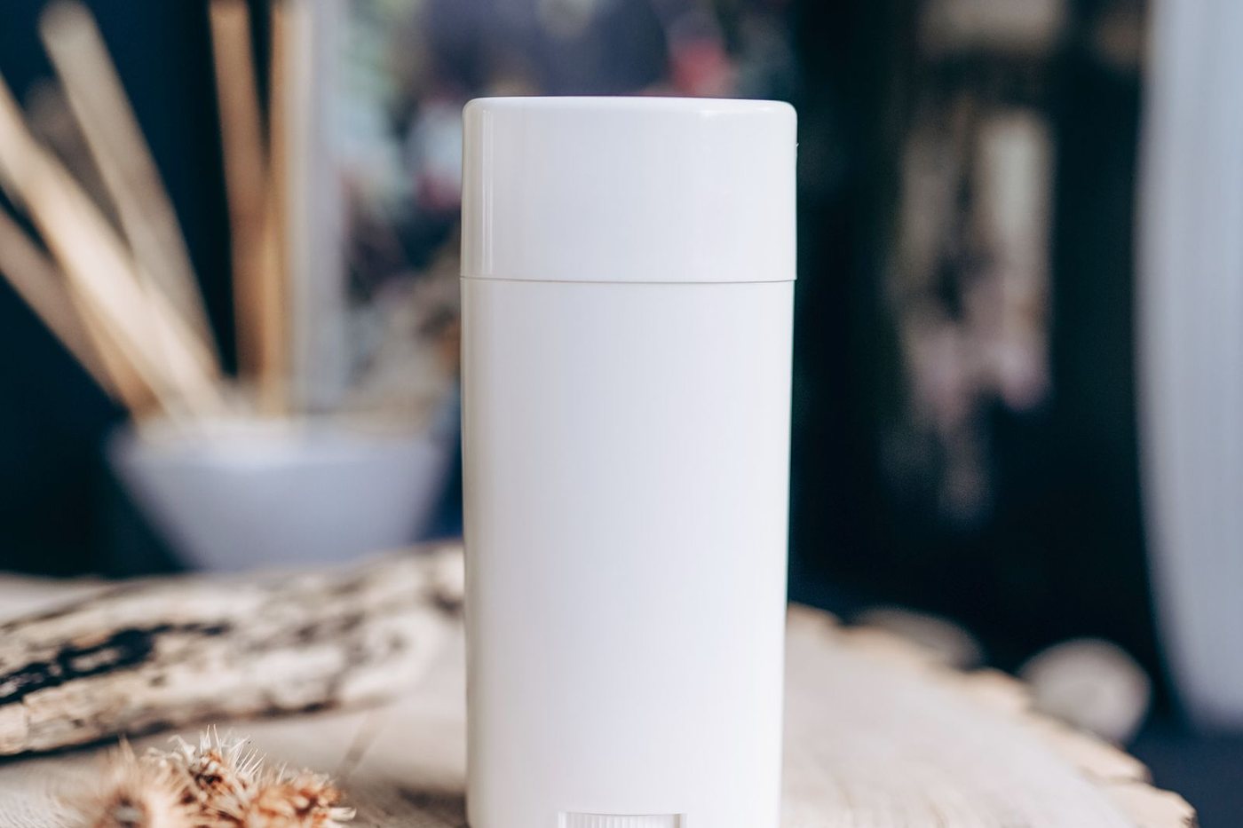 Close-up of a plain white deodorant container resting on a textured wooden surface.