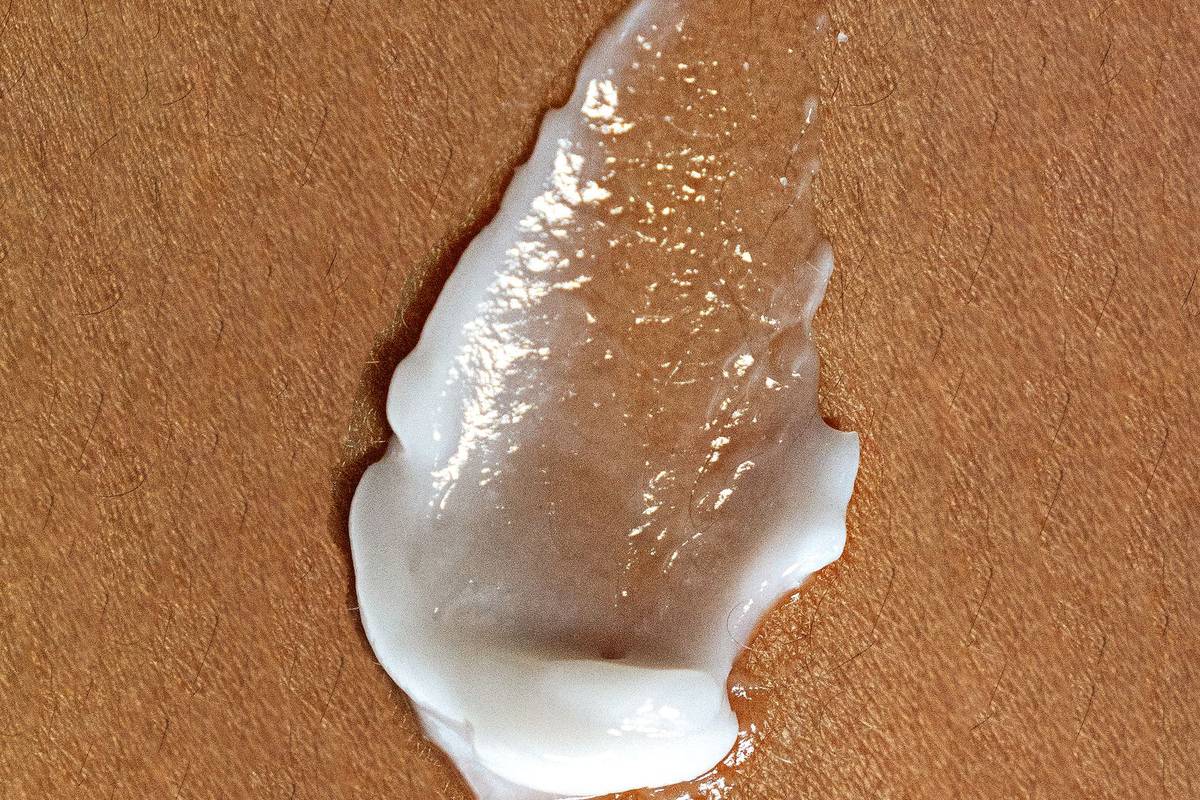 A smear of white skincare cream spread across skin showing its rich moisturising texture.