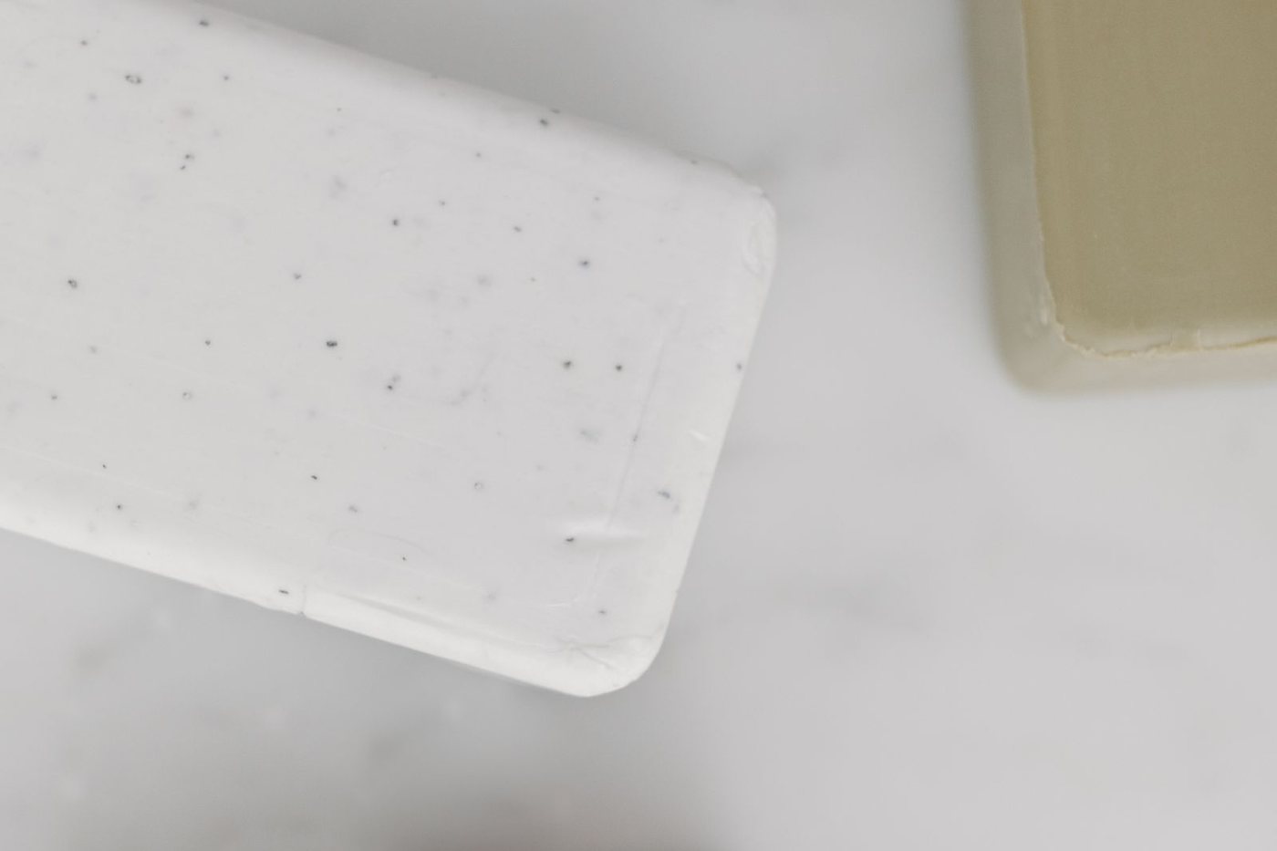 Assorted natural bar soaps in different colours and textures arranged on a light background.